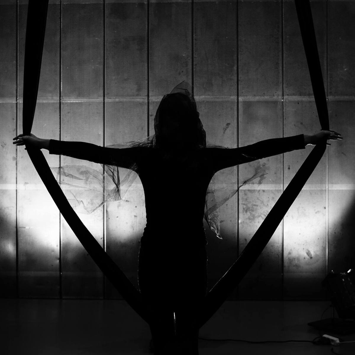 Black-and-white performance photograph of a silhouetted figure